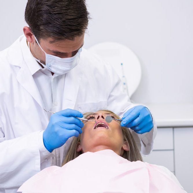 dentist-holding-equipment-while-cleaning-woman-teeth dentist-holding-equipment-while-cleaning-woman-teeth